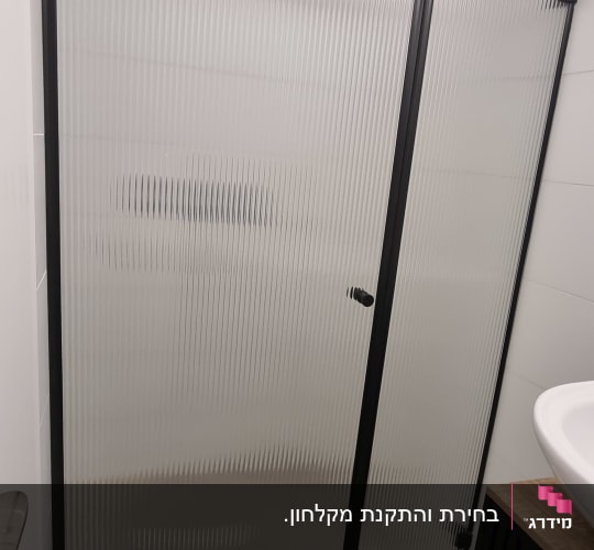 מקלחון חזית ממוסגר בשחור עם זכוכית פסים בחדר רחצה